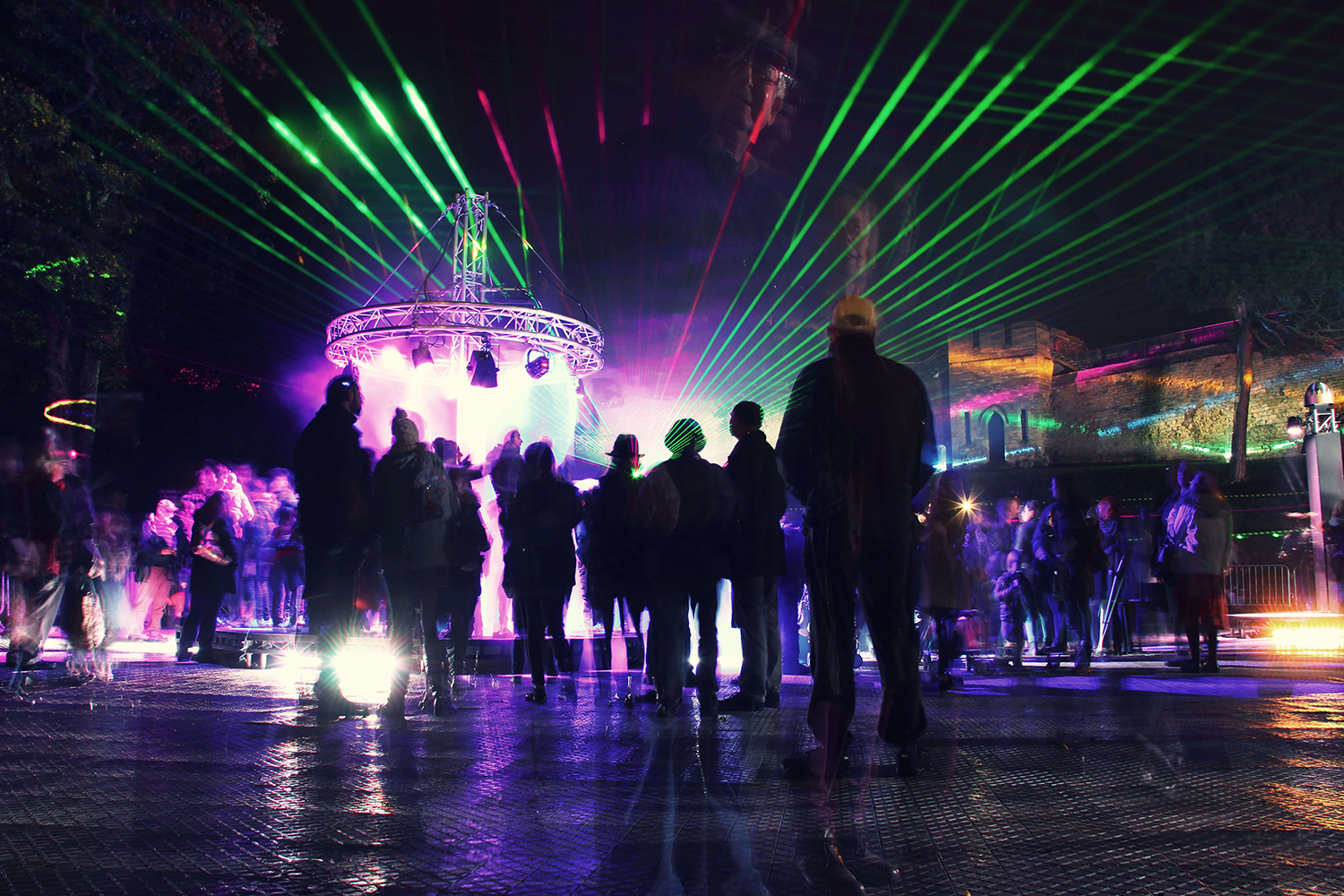 An outdoor art event for Frequency Festival sees people silhouetted against a backdrop of colourful lights and lasers