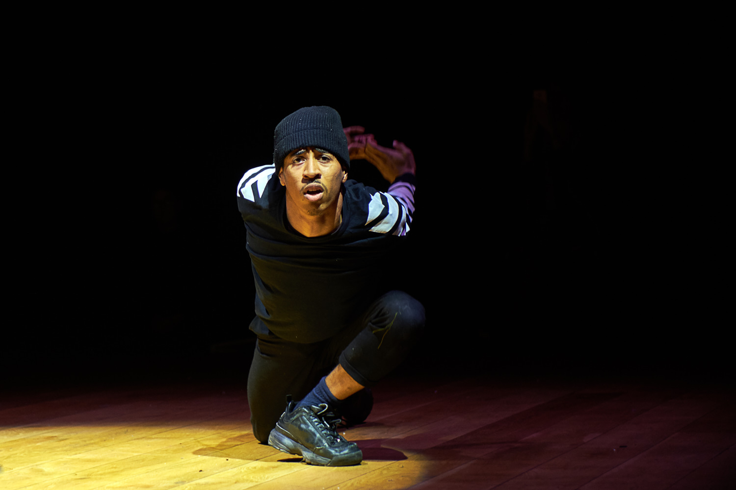 A young performer contorts his body with an earnest expression on his face