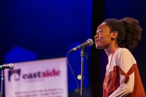 A young black woman speaks poetry onstage